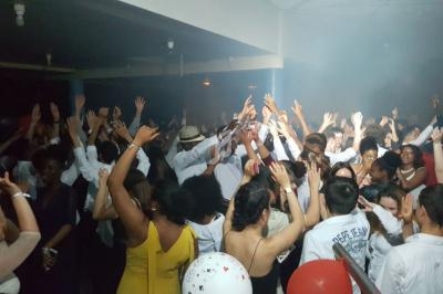 Groupe de personnes dansant dans une salle sombre, éclairée par des lumières tamisées, ambiance festive.