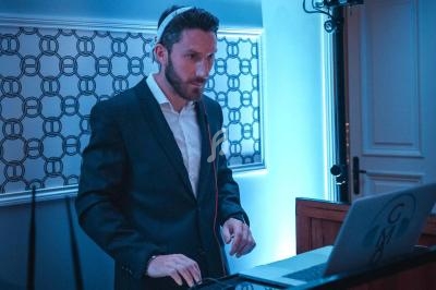 Un homme en costume utilise un ordinateur portable dans une pièce éclairée par une lumière bleue.