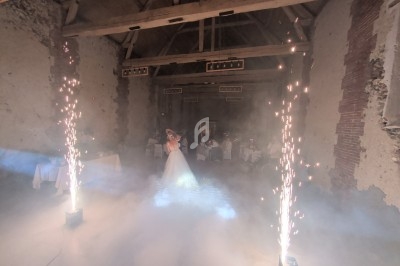 Une mariée danse au centre d'une salle en pierre, entourée de fumée et d'effets pyrotechniques.