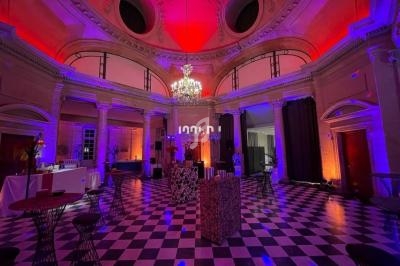 Salle circulaire avec plafond voûté, éclairage coloré, lustre central, sol en damier et mobilier pour réception.