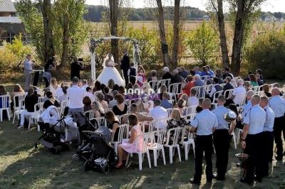 Cérémonie de mariage en plein air avec des invités assis sur des chaises blanches, entourés d'arbres et de nature.