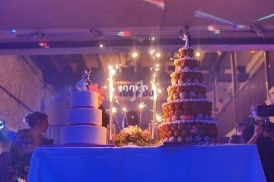 Deux gâteaux de fête décorés, dont une pièce montée, entourés de fontaines lumineuses dans une ambiance festive.