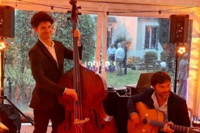 Quatre musiciens jouent du jazz dans une tente éclairée, avec contrebasse, guitare, saxophone et batterie.