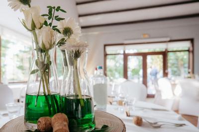 Terrasse extérieure d'un restaurant avec des tables et chaises sur un sol en pierre, entourée de verdure et arbres.