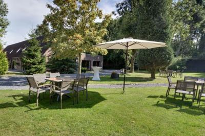 Terrasse extérieure d'un restaurant avec des tables et chaises sur un sol en pierre, entourée de verdure et arbres.
