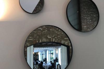 Terrasse extérieure d'un restaurant avec des tables et chaises sur un sol en pierre, entourée de verdure et arbres.