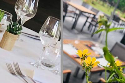 Terrasse extérieure d'un restaurant avec des tables et chaises sur un sol en pierre, entourée de verdure et arbres.