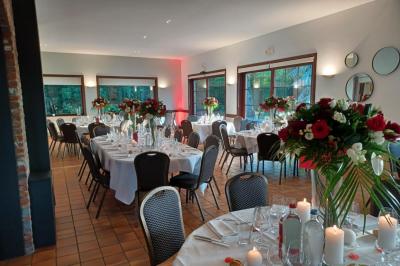 Terrasse extérieure d'un restaurant avec des tables et chaises sur un sol en pierre, entourée de verdure et arbres.