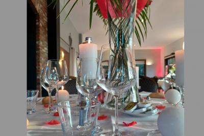Terrasse extérieure d'un restaurant avec des tables et chaises sur un sol en pierre, entourée de verdure et arbres.