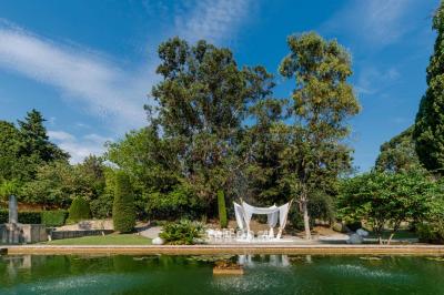 Jardin éclairé de nuit avec piscine, terrasse en pavés et bâtiments entourés de végétation.