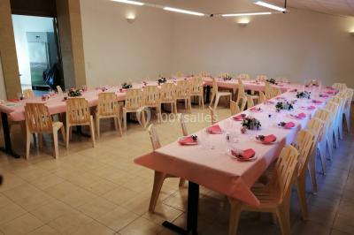 Groupe de personnes rassemblées dans une cour extérieure verdoyante devant un bâtiment en pierre avec des volets bleus.