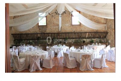 Groupe de personnes rassemblées dans une cour extérieure verdoyante devant un bâtiment en pierre avec des volets bleus.