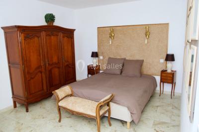 Groupe de personnes rassemblées dans une cour extérieure verdoyante devant un bâtiment en pierre avec des volets bleus.