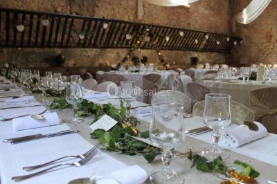 Groupe de personnes rassemblées dans une cour extérieure verdoyante devant un bâtiment en pierre avec des volets bleus.
