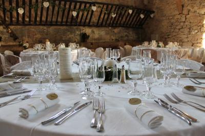 Groupe de personnes rassemblées dans une cour extérieure verdoyante devant un bâtiment en pierre avec des volets bleus.