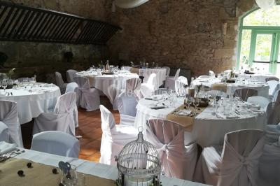 Groupe de personnes rassemblées dans une cour extérieure verdoyante devant un bâtiment en pierre avec des volets bleus.