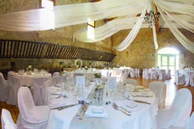 Groupe de personnes rassemblées dans une cour extérieure verdoyante devant un bâtiment en pierre avec des volets bleus.