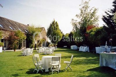 Salle de réception décorée avec des tables dressées, des guirlandes lumineuses et des arrangements floraux.