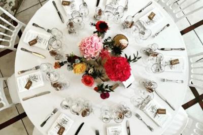Salle de réception décorée avec des tables dressées, des guirlandes lumineuses et des arrangements floraux.