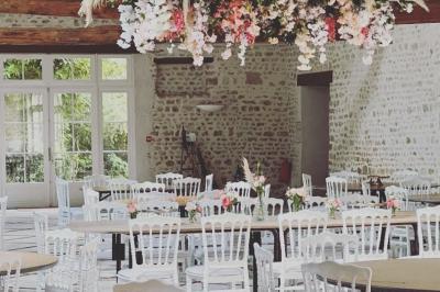 Salle de réception décorée avec des tables dressées, des guirlandes lumineuses et des arrangements floraux.
