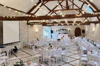 Salle de réception décorée avec des tables dressées, des guirlandes lumineuses et des arrangements floraux.