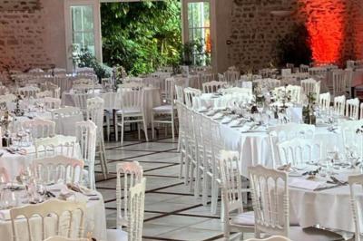 Salle de réception décorée avec des tables dressées, des guirlandes lumineuses et des arrangements floraux.