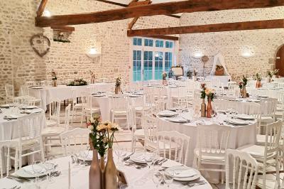Salle de réception décorée avec des tables dressées, des guirlandes lumineuses et des arrangements floraux.