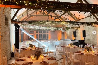 Salle de réception décorée avec des tables dressées, des guirlandes lumineuses et des arrangements floraux.