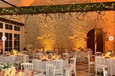 Salle de réception décorée avec des tables dressées, des guirlandes lumineuses et des arrangements floraux.