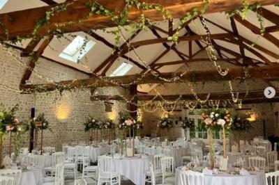 Salle de réception décorée avec des tables dressées, des guirlandes lumineuses et des arrangements floraux.