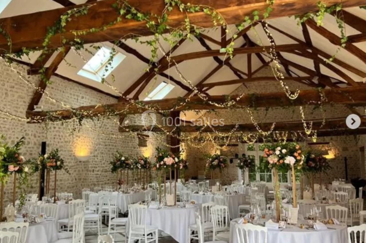 Salle de réception décorée avec des tables dressées, des guirlandes lumineuses et des arrangements floraux.