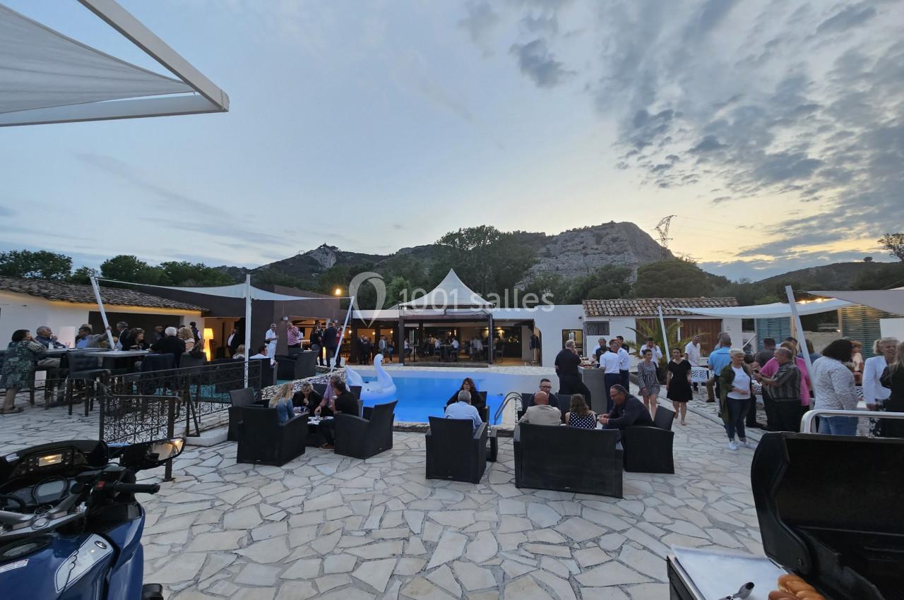 Personnes réunies autour d'une piscine en extérieur au crépuscule, avec des collines en arrière-plan.