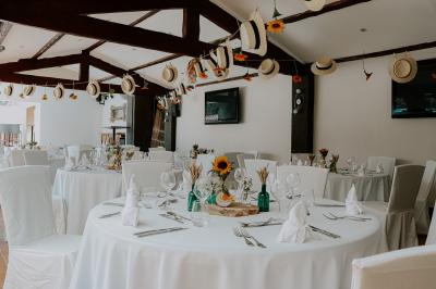 Un groupe de musiciens joue sur une petite scène extérieure sous un ciel bleu, entouré de décorations en bois.