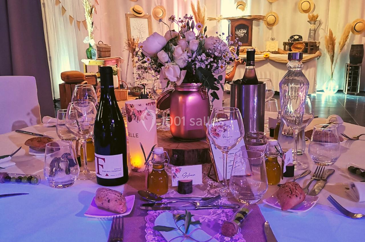 Table décorée pour un repas festif avec fleurs, bouteilles de vin, verres, pain et accessoires élégants.