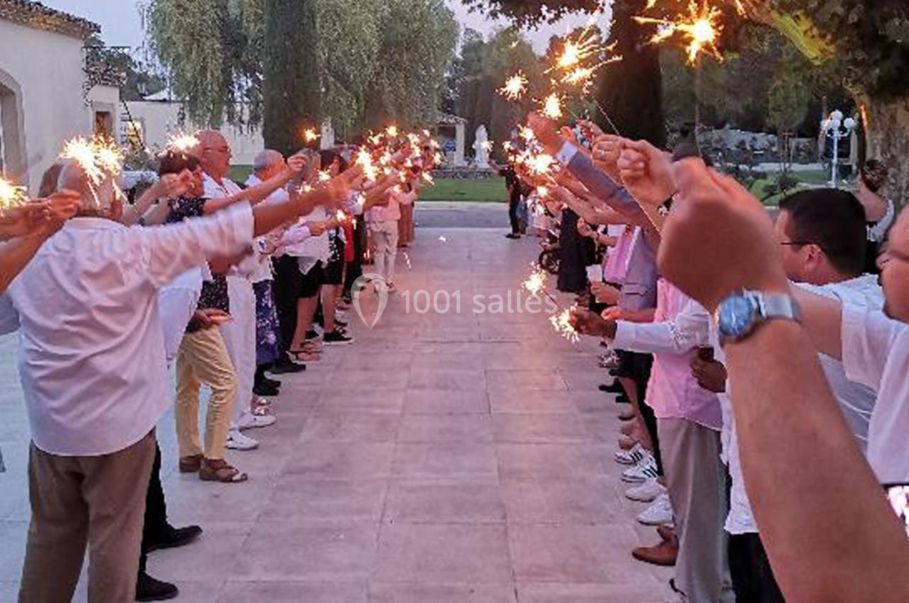 Des personnes alignées des deux côtés d'une allée tiennent des cierges magiques allumés au crépuscule.