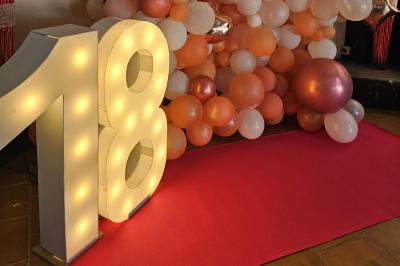 Un groupe de musiciens joue sur une petite scène extérieure sous un ciel bleu, entouré de décorations en bois.