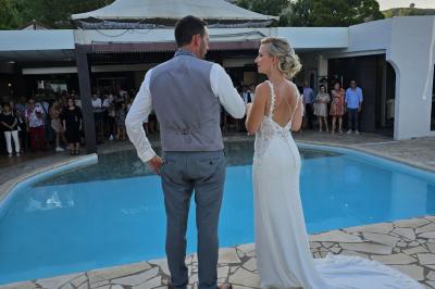 Un groupe de musiciens joue sur une petite scène extérieure sous un ciel bleu, entouré de décorations en bois.