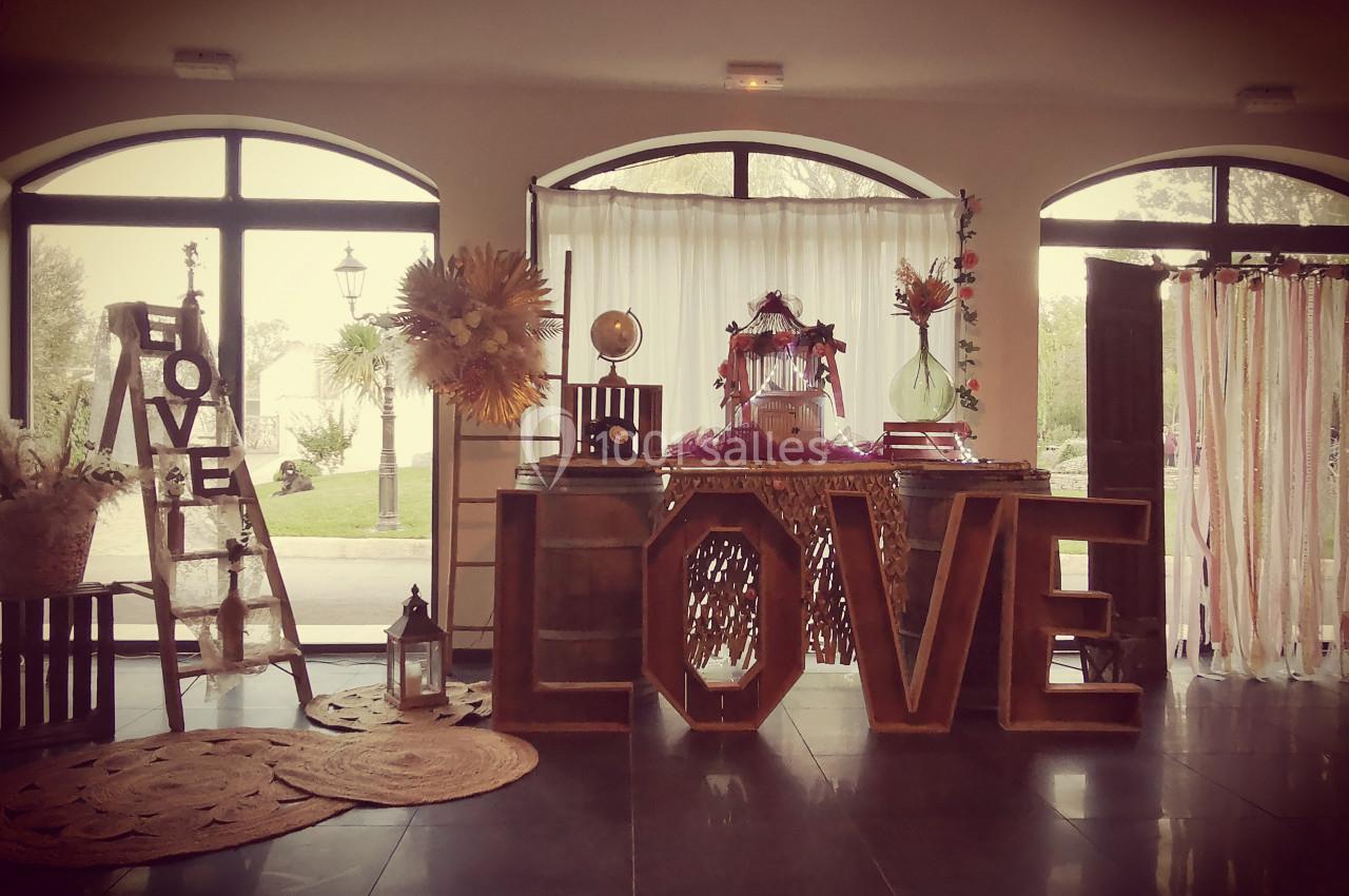 Décoration intérieure avec des lettres géantes formant ’LOVE’, des fleurs et des éléments rustiques en bois.
