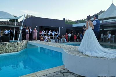 Un groupe de musiciens joue sur une petite scène extérieure sous un ciel bleu, entouré de décorations en bois.
