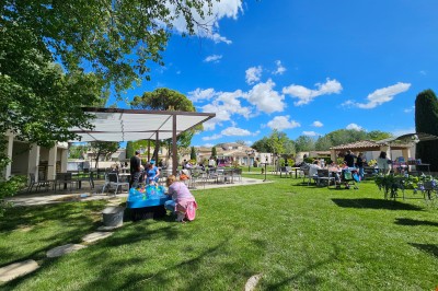 Un groupe de musiciens joue sur une petite scène extérieure sous un ciel bleu, entouré de décorations en bois.