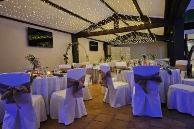 Un groupe de musiciens joue sur une petite scène extérieure sous un ciel bleu, entouré de décorations en bois.