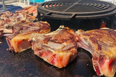 Un groupe de musiciens joue sur une petite scène extérieure sous un ciel bleu, entouré de décorations en bois.
