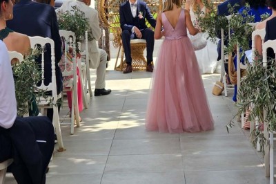 Un groupe de musiciens joue sur une petite scène extérieure sous un ciel bleu, entouré de décorations en bois.