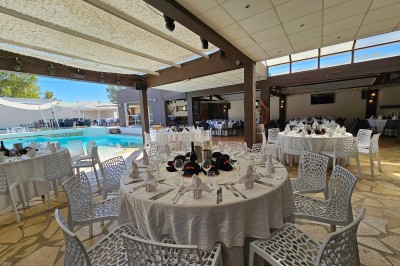 Un groupe de musiciens joue sur une petite scène extérieure sous un ciel bleu, entouré de décorations en bois.