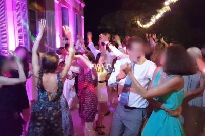 Des personnes dansent en soirée en extérieur, éclairées par des lumières colorées et des guirlandes lumineuses.