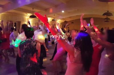 Des personnes dansent dans une salle éclairée par des lumières colorées lors d'un événement festif.