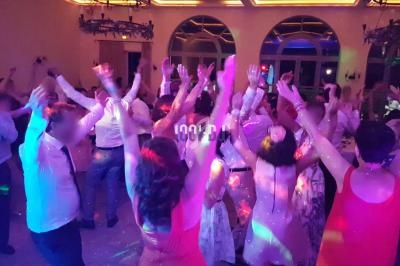 Groupe de personnes dansant sous des lumières colorées dans une salle de réception en soirée.