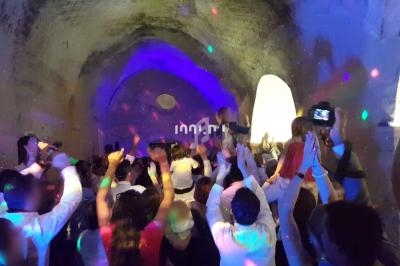 Groupe de personnes dans une salle voûtée, dansant sous des lumières colorées lors d'une fête.