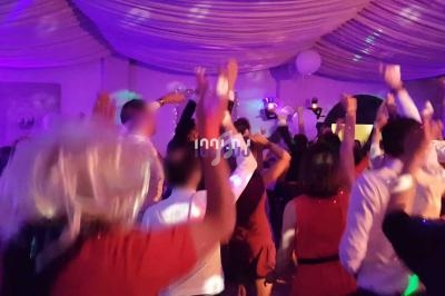 Groupe de personnes dansant sous des lumières colorées dans une salle décorée avec un plafond drapé.