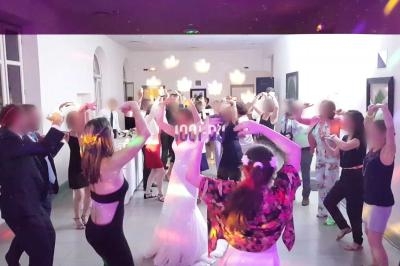 Des personnes dansent dans une salle éclairée par des lumières colorées, lors d'un événement festif.